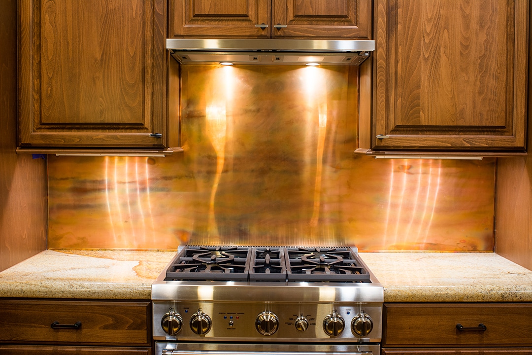 A stainless steel gas stove in a kitchen with wooden cabinets.