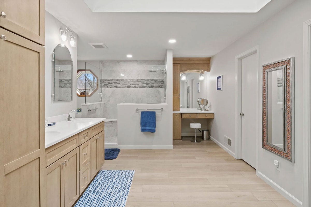 A modern bathroom interior featuring wooden furniture and a large mirror. The bathroom has a clean and minimalist design.