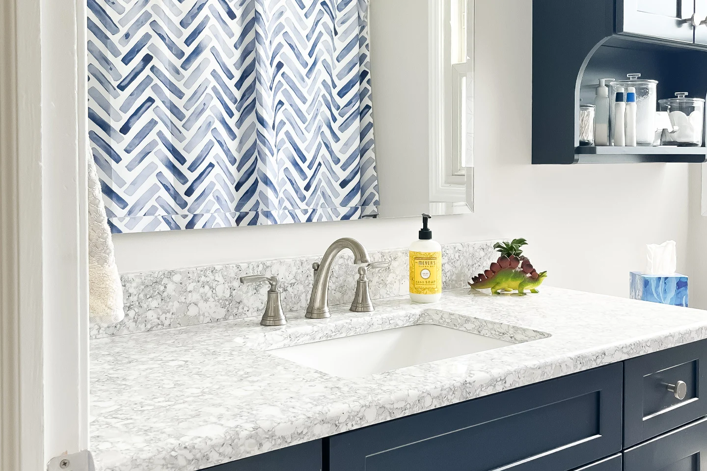 Modern bathroom sink with blue cabinets and marble countertop. The sink is clean and shiny.