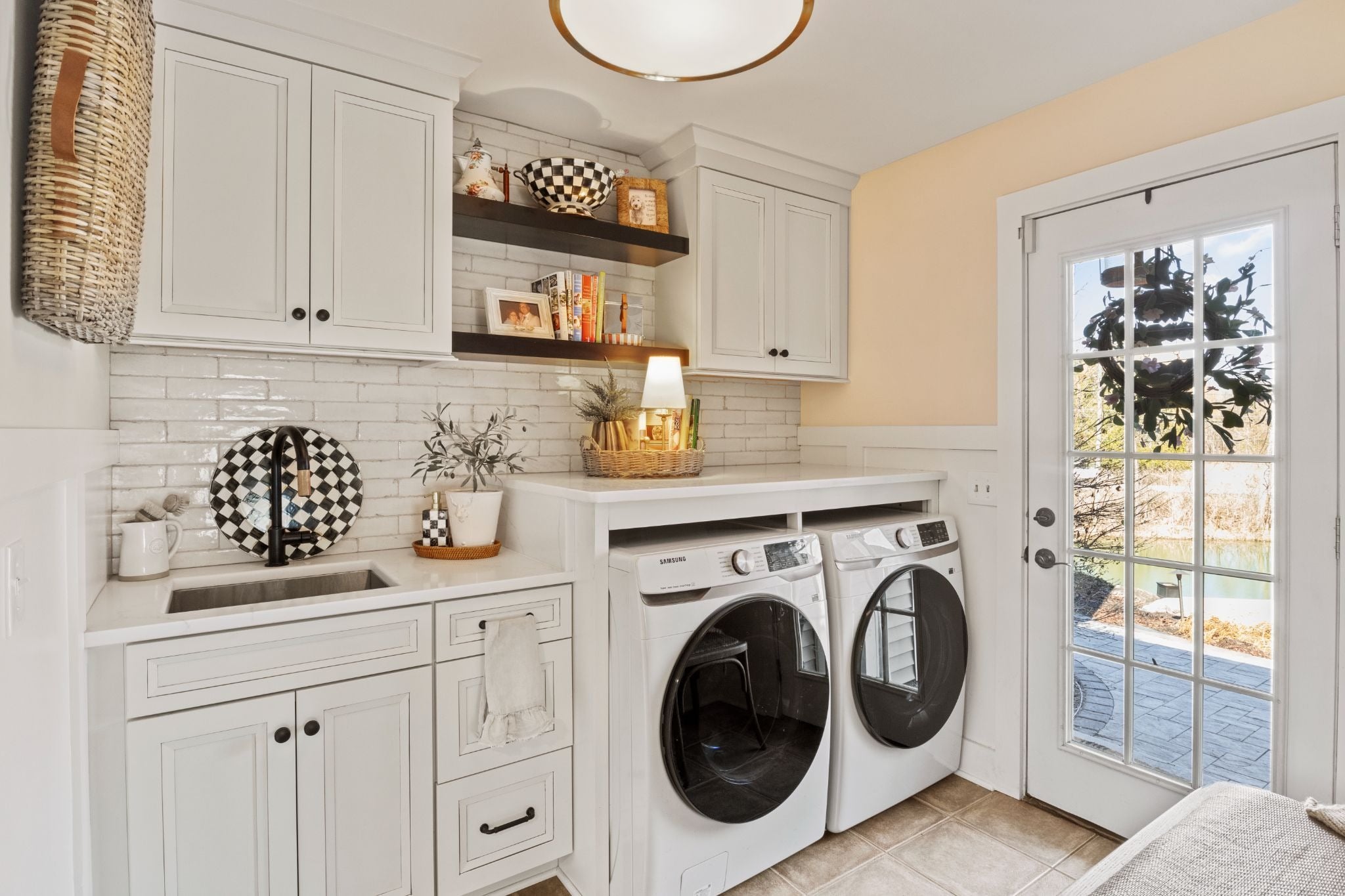 Laundry room with white cabinets and washing machines. A door leading outside is on the right.