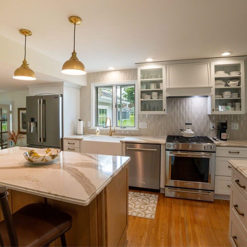 Modern Kitchen with White Cabinets and Island A modern kitchen with white cabinets and a large island. The kitchen features stainless steel appliances and a bowl of fruit on the island.