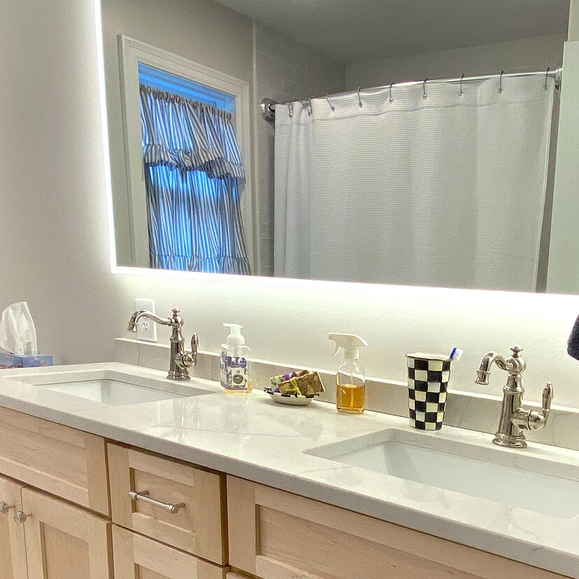 Double sink vanity with silver faucets and light wood cabinets