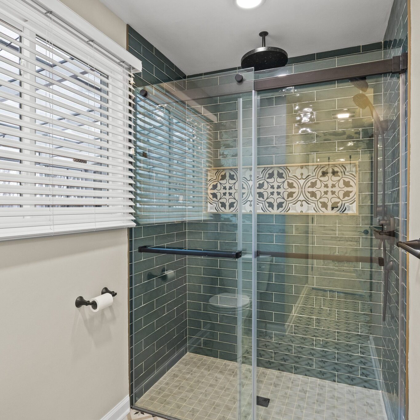 Bathroom with glass shower, tiled walls and floor.