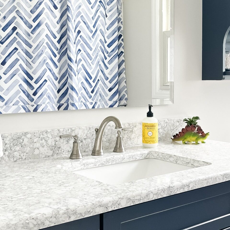 Modern bathroom sink with blue cabinets and marble countertop. The sink is clean and shiny.