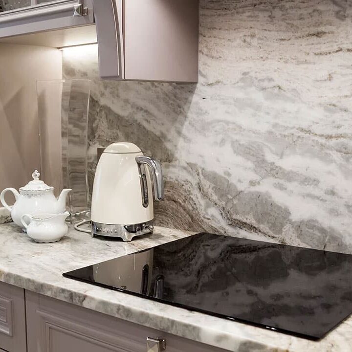 Induction cooktop and white kettle on marble countertop. Modern kitchen design.